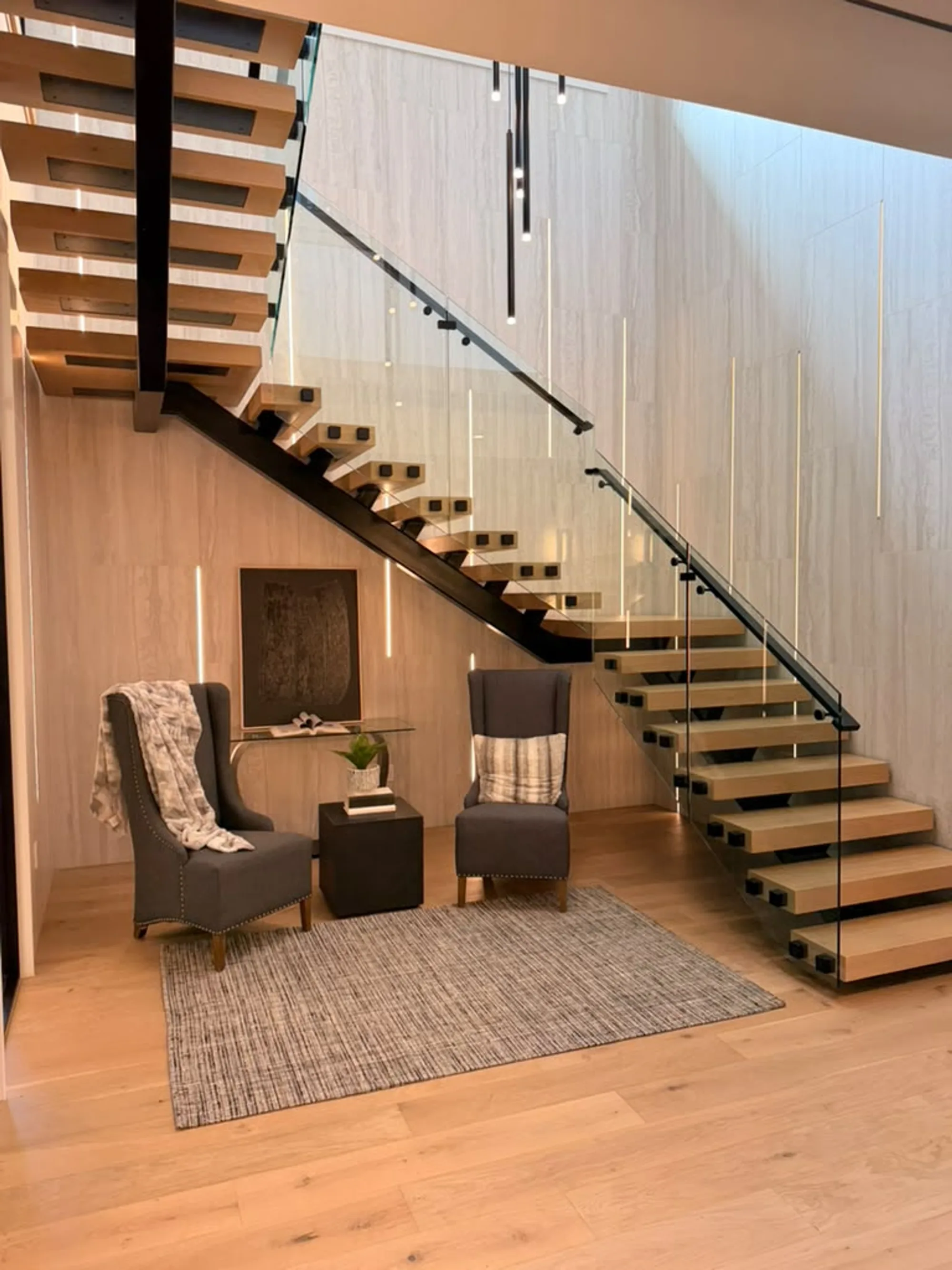 Floating staircase with glass railing and wide-plank engineered wood flooring